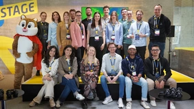 A group photo with 19 people and a mascot.