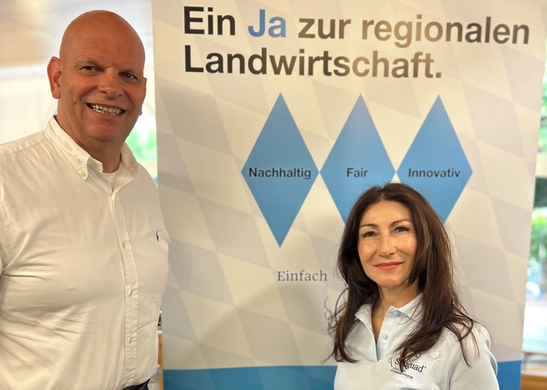 A man and a woman are standing in front of a billboard.