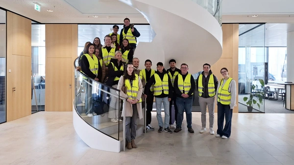 Gruppenfoto auf einer Wendeltreppe, alle Personen tragen gelbe Warnwesten.